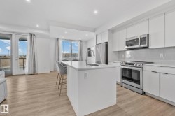 Kitchen with white cabinets, appliances with stainless steel finishes, a center island with sink, and recessed lighting - 