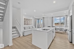 Kitchen with an island with sink, light wood-style floors, french doors, white cabinets, and appliances with stainless steel finishes - 