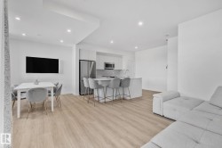 Living area with recessed lighting and light wood-style floors - 