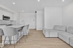 Kitchen featuring white cabinets, an island with sink, a kitchen bar, stainless steel microwave, and open floor plan - 