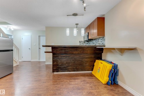 Kitchen featuring freestanding refrigerator, decorative backsplash, pendant lighting, brown cabinetry, and dark wood finished floors - 18404 97A Avenue, Edmonton, AB - Indoor Photo Showing Kitchen