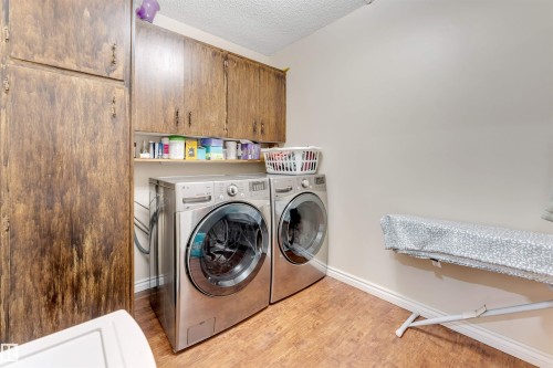 Washroom featuring a textured ceiling, light wood-style floors, washer and dryer, and cabinet space - 18404 97A Avenue, Edmonton, AB - Indoor Photo Showing Laundry Room