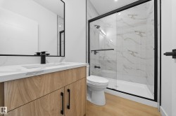 Bathroom with vanity, a marble finish shower, and light wood-style flooring - 