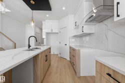 Kitchen with light stone countertops, extractor fan, light wood-style floors, modern cabinets, and white cabinetry - 
