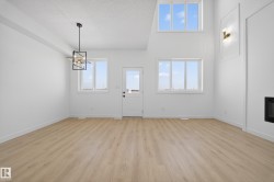 Entryway featuring light wood-style floors, a chandelier, a high ceiling, and a glass covered fireplace - 
