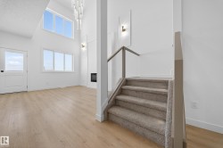 Entryway with light wood-type flooring, stairs, a towering ceiling, and a glass covered fireplace - 
