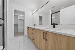 Full bath featuring light marble finish floors, a marble finish shower, double vanity, and a walk in closet - 