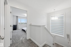 Corridor featuring dark colored carpet, a textured ceiling, and an upstairs landing - 