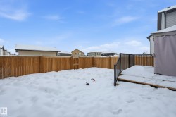 Yard covered in snow with a fenced backyard, a wooden deck, and a residential view - 