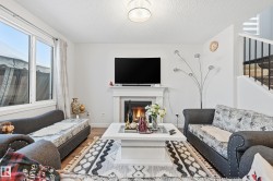 Living room with wood finished floors, a tiled fireplace, a textured ceiling, and stairs - 