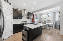 Kitchen featuring dark cabinetry, wall chimney exhaust hood, decorative backsplash, stainless steel electric range, and light wood finished floors - 