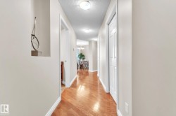 Hall featuring a textured ceiling, light wood finished floors, and a chandelier - 