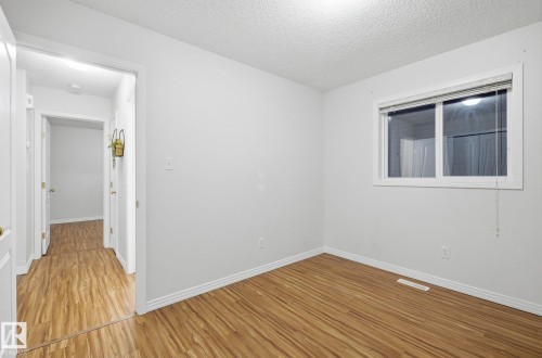 Empty room featuring a textured ceiling and wood finished floors - 608 87 St, Edmonton, AB - Indoor Photo Showing Other Room