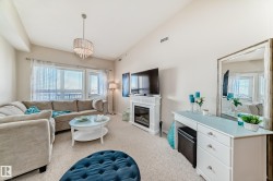 Living room with lofted ceiling, a glass covered fireplace, light colored carpet, and a chandelier - 