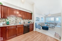 Kitchen featuring dishwasher, a chandelier, light wood-type flooring, vaulted ceiling, and backsplash - 