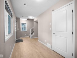 Hallway with a textured ceiling, light wood-type flooring, and stairway - 