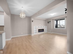 Unfurnished living room featuring a glass covered fireplace, a chandelier, and light wood finished floors - 