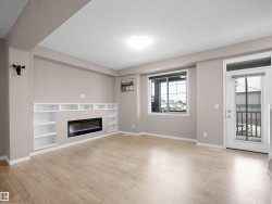 Unfurnished living room with a textured ceiling, a glass covered fireplace, light wood-style flooring, and built in shelves - 