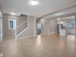Unfurnished living room featuring stairs, light wood-style flooring, a textured ceiling, and a chandelier - 