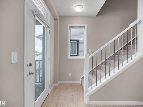 Entryway featuring stairs, light wood-style floors, and a textured ceiling - 2080 Wonnacott Way, Edmonton, AB - Indoor Photo Showing Other Room