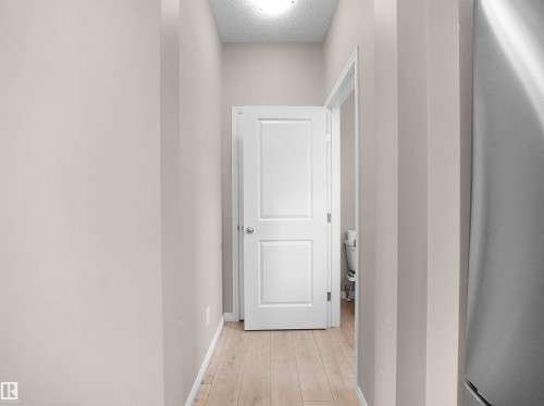 Hall with light wood-type flooring and a textured ceiling - 2080 Wonnacott Way, Edmonton, AB 