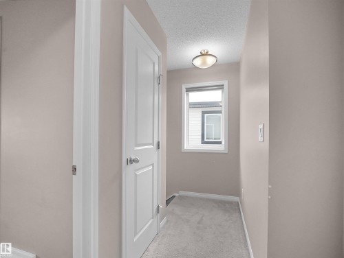 Hallway featuring light colored carpet and a textured ceiling - 2080 Wonnacott Way, Edmonton, AB - Indoor Photo Showing Other Room