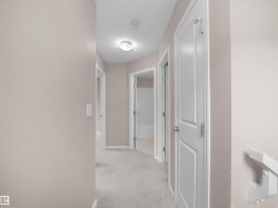 Hall with light colored carpet and a textured ceiling - 