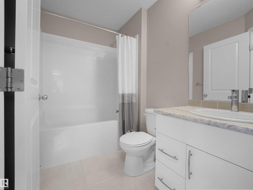 Bathroom featuring shower / tub combo, vanity, a textured ceiling, and light tile patterned floors - 2080 Wonnacott Way, Edmonton, AB - Indoor Photo Showing Bathroom