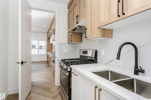 Kitchen featuring stainless steel appliances, light stone counters, under cabinet range hood, tasteful backsplash, and recessed lighting - 220 Edgemont Green Green, Edmonton, AB - Indoor Photo Showing Kitchen With Double Sink