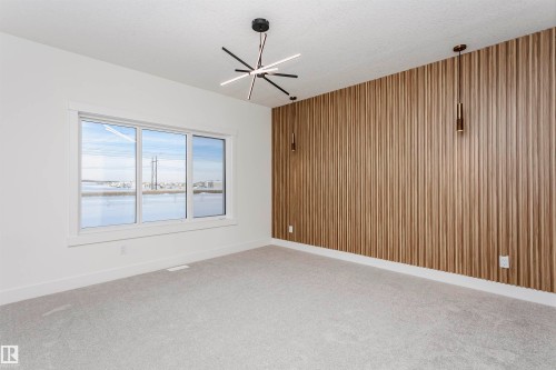 Unfurnished room with wood walls, light colored carpet, an accent wall, a textured ceiling, and a chandelier - 220 Edgemont Green Green, Edmonton, AB - Indoor Photo Showing Other Room