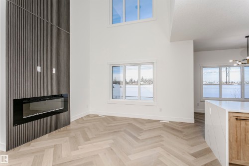 Unfurnished living room featuring a glass covered fireplace, a high ceiling, and a chandelier - 220 Edgemont Green Green, Edmonton, AB - Indoor Photo Showing Other Room With Fireplace