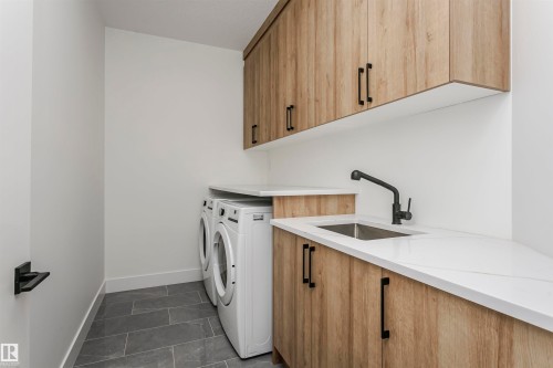 Washroom with cabinet space, washing machine and dryer, and dark tile patterned floors - 220 Edgemont Green Green, Edmonton, AB - Indoor Photo Showing Laundry Room