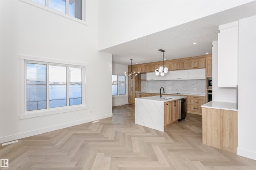 Kitchen featuring a chandelier, light stone countertops, a center island with sink, decorative light fixtures, and backsplash - 220 Edgemont Green Green, Edmonton, AB - Indoor Photo Showing Other Room