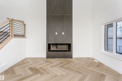 Empty room featuring a glass covered fireplace, stairway, and a high ceiling - 220 Edgemont Green Green, Edmonton, AB - Indoor With Fireplace
