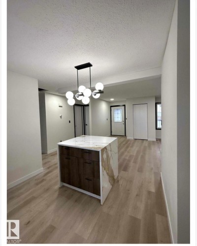 Kitchen featuring a textured ceiling, decorative light fixtures, light wood-style floors, light stone countertops, and modern cabinets - 11628 151 Avenue Nw, Edmonton, AB - Indoor
