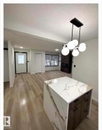 Kitchen featuring light wood-type flooring, open floor plan, hanging light fixtures, modern cabinets, and a kitchen island - 