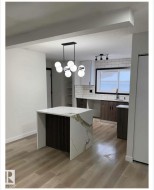 Kitchen featuring decorative backsplash, hanging light fixtures, light wood-style floors, and modern cabinets - 