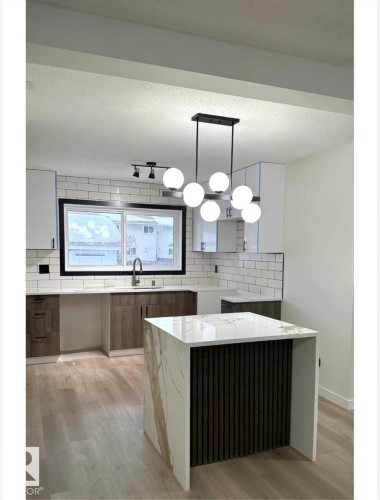 Kitchen with a textured ceiling, light stone countertops, decorative light fixtures, and modern cabinets - 11628 151 Avenue Nw, Edmonton, AB - Indoor Photo Showing Kitchen