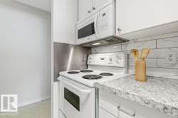 Kitchen with white appliances, white cabinetry, and light countertops - 