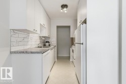 Kitchen with light flooring, white appliances, tasteful backsplash, light countertops, and white cabinets - 