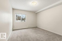Spare room with a textured ceiling, light colored carpet, and a baseboard heating unit - 