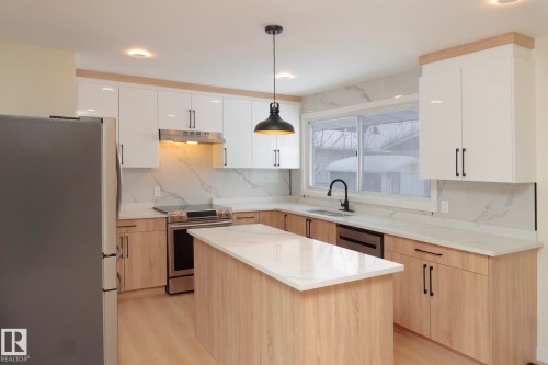 Kitchen with appliances with stainless steel finishes, light brown cabinets, decorative light fixtures, a center island, and recessed lighting - 13711 133 Avenue, Edmonton, AB - Indoor Photo Showing Kitchen