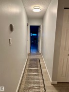 Hall featuring light wood-style flooring and a textured ceiling - 