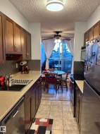 Kitchen featuring stainless steel appliances, light countertops, decorative backsplash, a ceiling fan, and light tile patterned floors - 