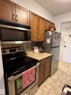 Kitchen with appliances with stainless steel finishes, a textured ceiling, light tile patterned floors, and decorative backsplash - 