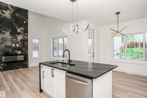 Kitchen with white cabinetry, stainless steel dishwasher, a chandelier, and decorative light fixtures - 804 Elderberry Crest, Edmonton, AB - Indoor Photo Showing Kitchen With Double Sink