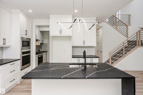 Kitchen featuring a kitchen island with sink, stainless steel appliances, hanging light fixtures, light wood-type flooring, and recessed lighting - 804 Elderberry Crest, Edmonton, AB - Indoor Photo Showing Other Room