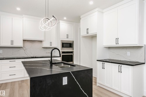 Kitchen with backsplash, an island with sink, stainless steel appliances, hanging light fixtures, and recessed lighting - 804 Elderberry Crest, Edmonton, AB - Indoor Photo Showing Kitchen With Double Sink With Upgraded Kitchen
