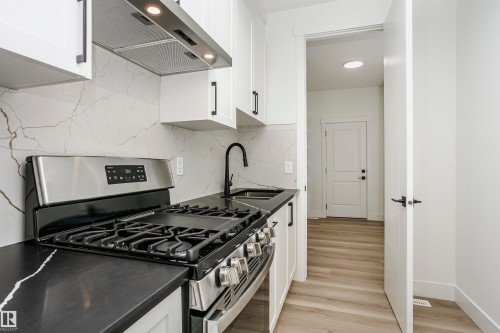 Kitchen featuring stainless steel range with gas cooktop, extractor fan, white cabinetry, and tasteful backsplash - 804 Elderberry Crest, Edmonton, AB - Indoor Photo Showing Kitchen With Upgraded Kitchen
