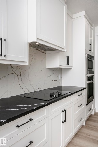 Kitchen with white cabinetry, stainless steel appliances, light wood finished floors, and tasteful backsplash - 804 Elderberry Crest, Edmonton, AB - Indoor Photo Showing Kitchen